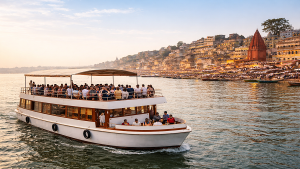 Private cruise boat sailing on Ganga River in Varanasi with tourists enjoying scenic views of historic ghats